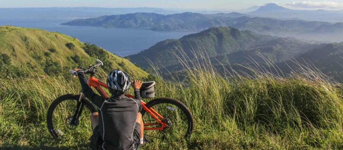 Biker on top of a mountain looking over the ocean contemplating mountain biking techniques