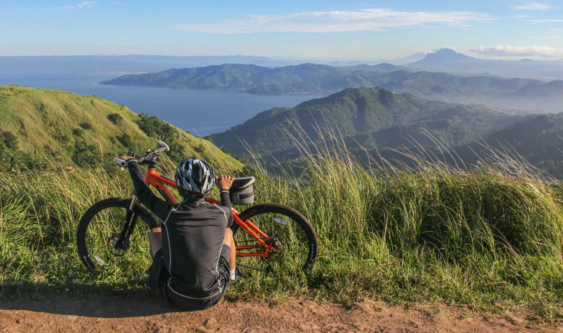 Biker on top of a mountain looking over the ocean contemplating mountain biking techniques